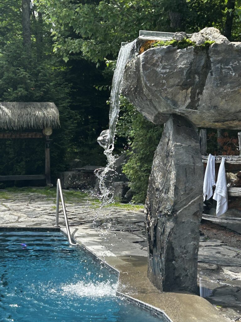 Chute d’eau en pierre vers piscine extérieure