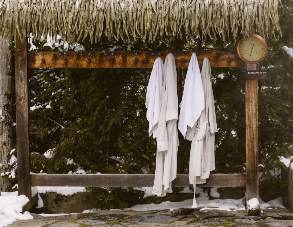 Peignoirs blancs suspendus près d’un spa extérieur enneigé
