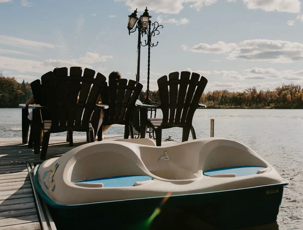 Pédalo au quai devant lac et chaises Adirondack