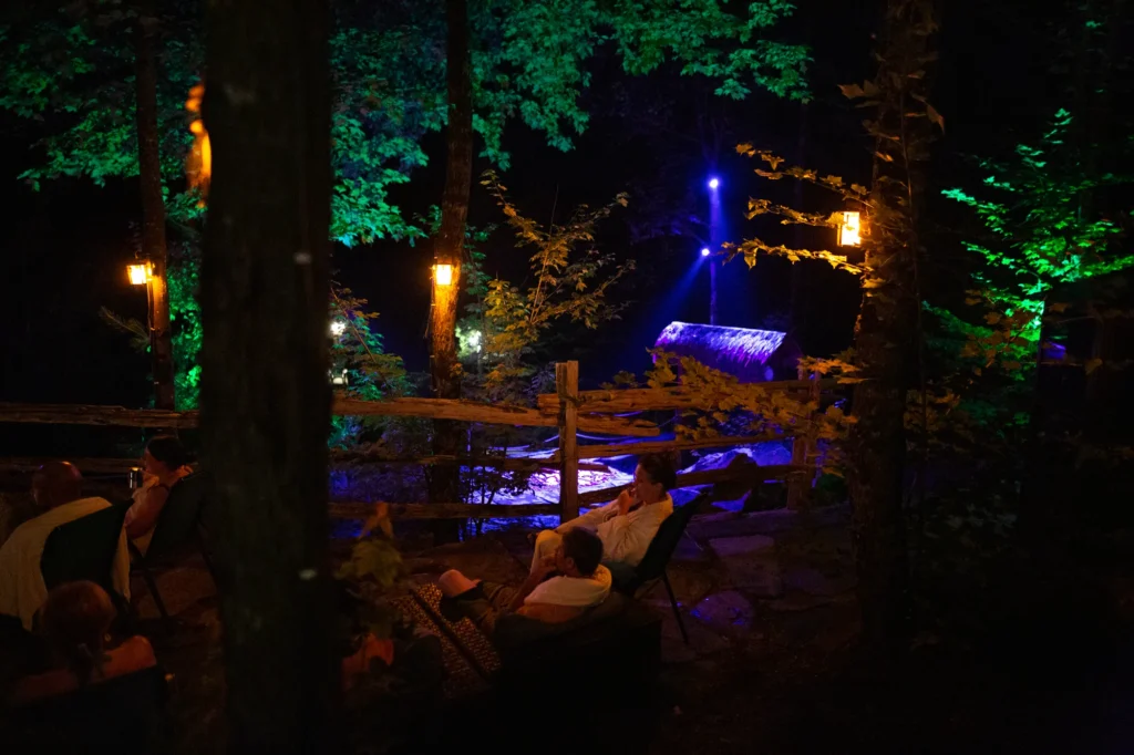 Forêt illuminée la nuit avec cascade et visiteurs