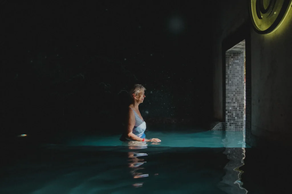 Femme relaxant dans une piscine intérieure sombre