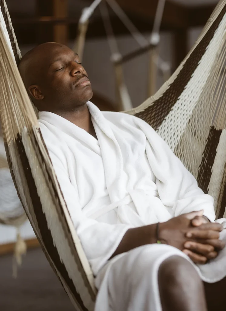 Homme en peignoir relaxant dans un hamac