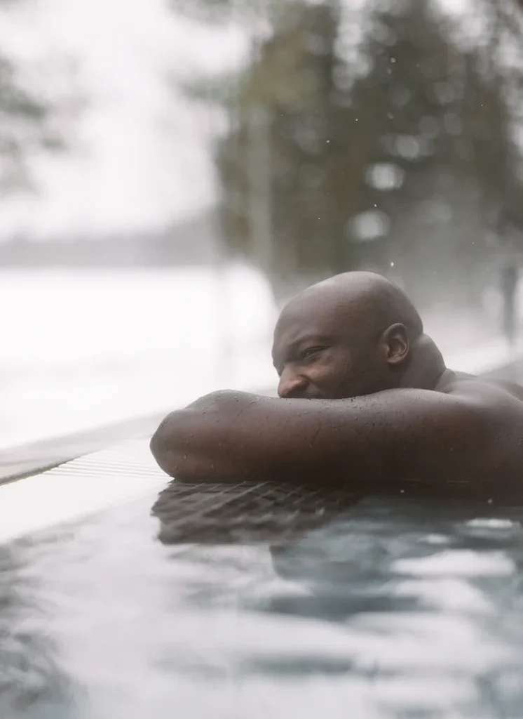 Homme appuyé au bord d’une piscine extérieure